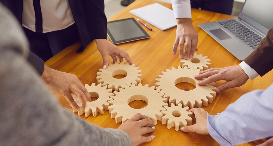 cogs on a table being turned by different hands showing integration