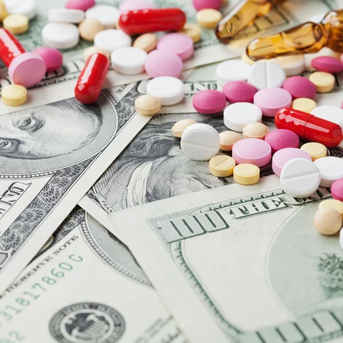 Heap of pharmaceutical drug and medicine pills scattered on dollar cash money, cost of drug abuse concept