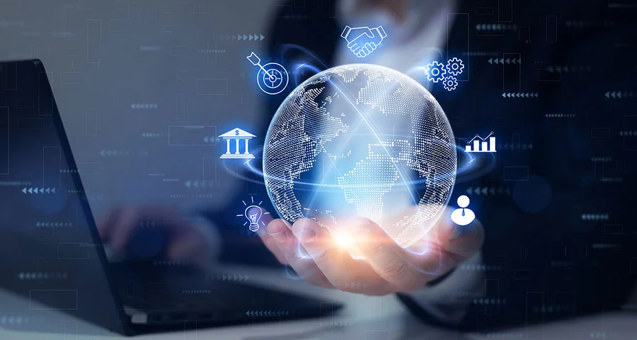 A hand holds a glowing sci-fi globe with blue icons around it, while the other operates a computer