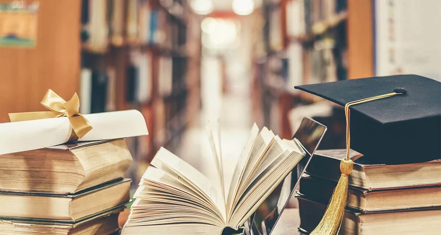 graduation cap and diploma sitting on top of Criminal Justice books in a library