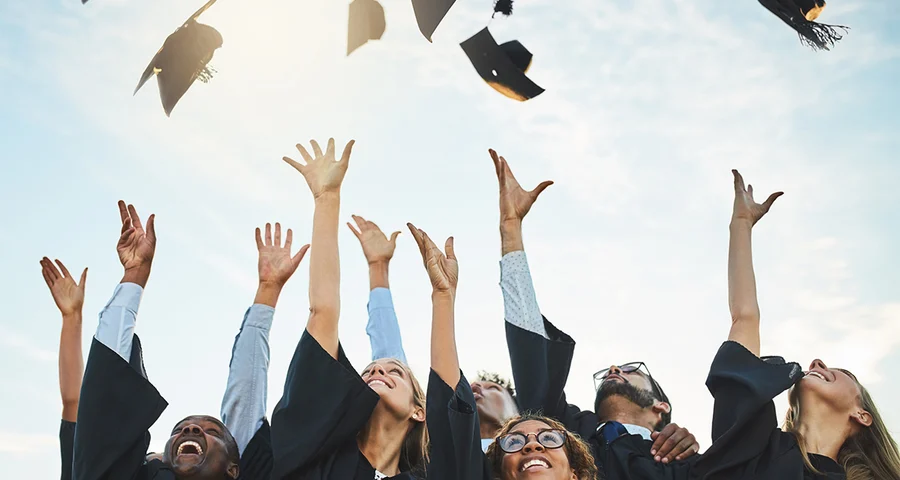 students celebrating graduation throwing caps in the sky