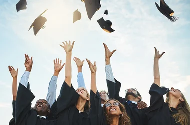 students celebrating graduation throwing caps in the sky