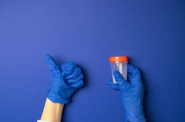 Gloved hands holding a drug test sample and giving a thumbs up