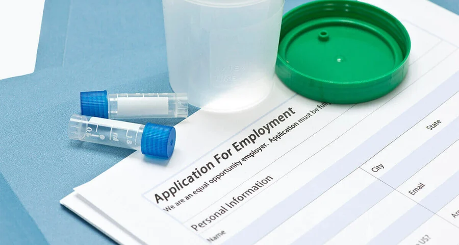 drug testing receptacles sitting on top of an application for employment