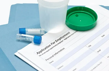 drug testing receptacles sitting on top of an application for employment