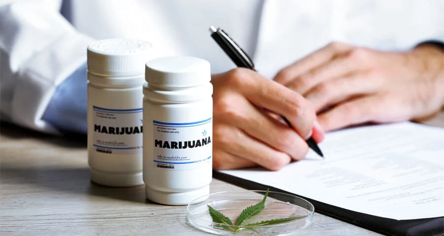 Doctor writing on prescription blank and bottle with medical cannabis on table close up