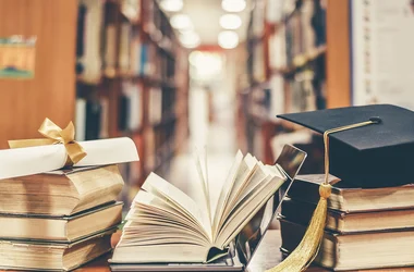 stacks of books, a graduation cap, and a diploma