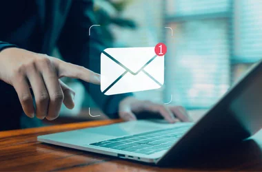 business professional touching floating email notification icon above laptop