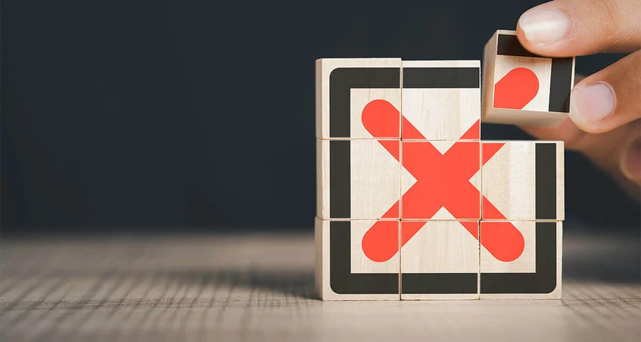 hand stacking wooden blocks with a bold red x painting