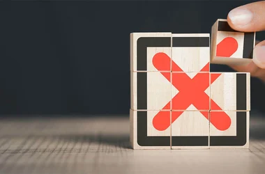 hand stacking wooden blocks with a bold red x painting