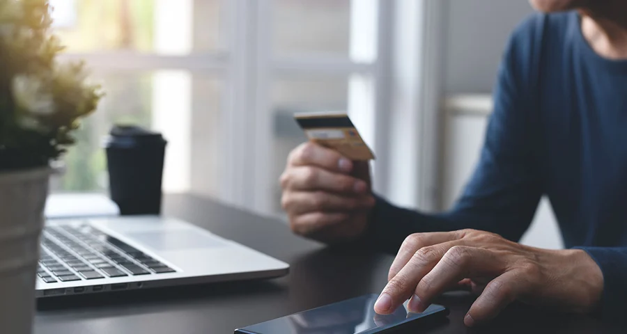 Werkende man checkt creditcard koffie laptop