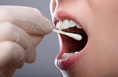 Gloved hand collecting an oral fluid sample