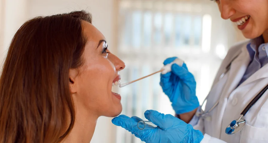 Medical technician collecting an oral fluid specimen from a patient