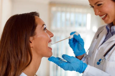 Medical technician collecting an oral fluid specimen from a patient