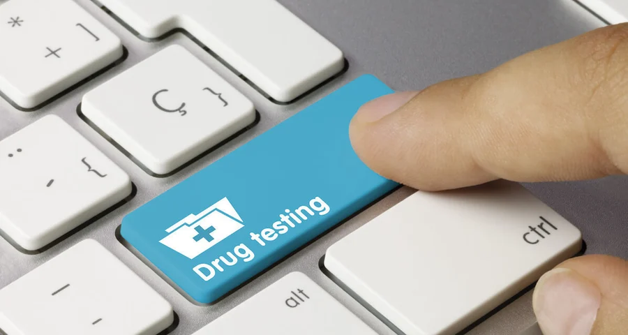 Finger pressing a button on a keyboard labeled "Drug Testing"