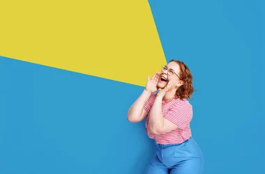 Happy young woman rejoices success isolated blue background
