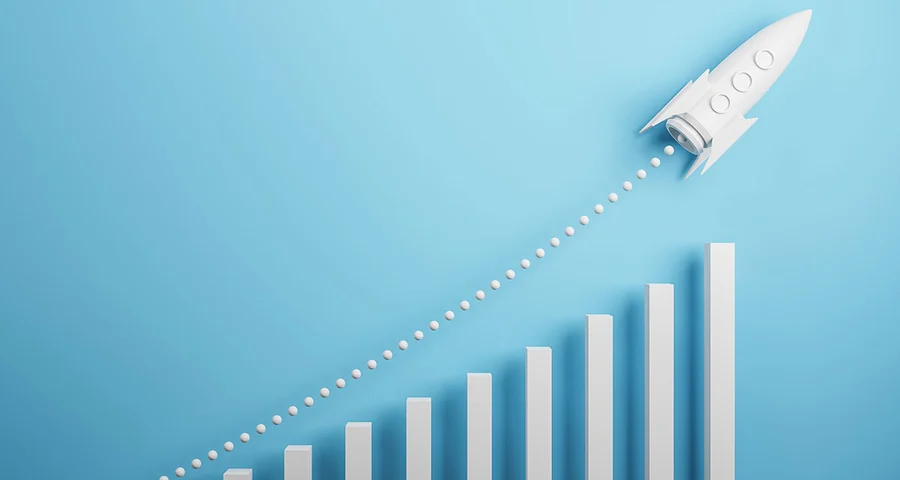 paper rocket ship taking off over an increasing bar graph symbolizing growth
