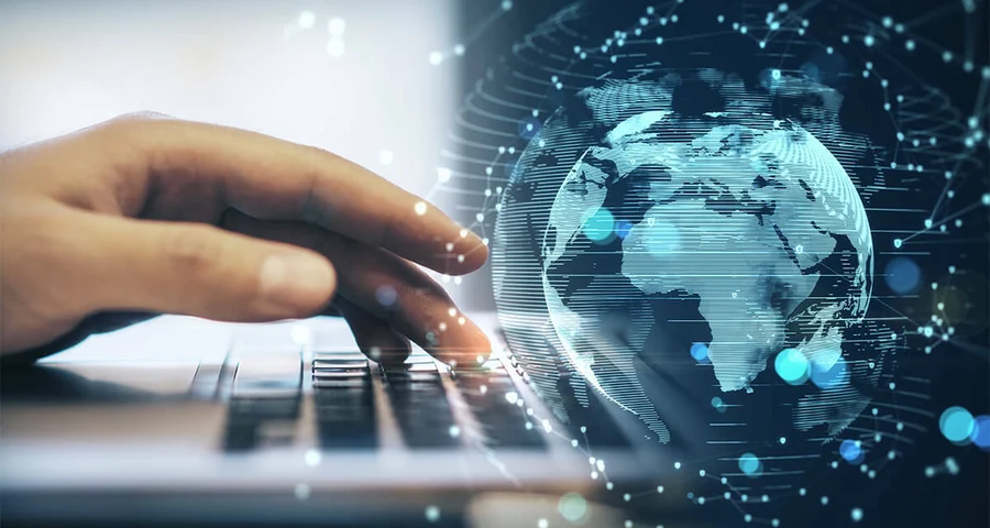 person working on a laptop with a digital globe image