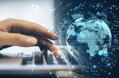 person working on a laptop with a digital globe image