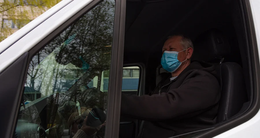 Truck driver behind the wheel wearing a medical mask