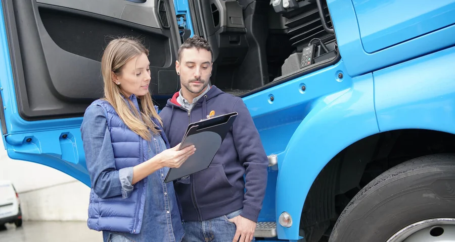 Transportation compliance worker reviewing a clipboard with a driver