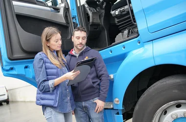 Transportation compliance worker reviewing a clipboard with a driver