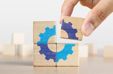Hand putting the last piece of wooden blocks with gear icon