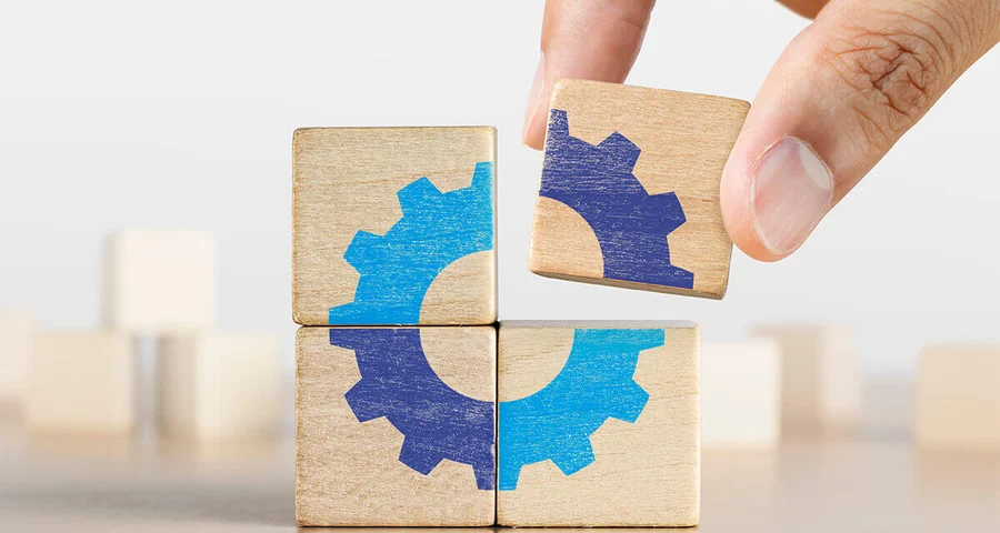Hand putting the last piece of wooden blocks with gear icon