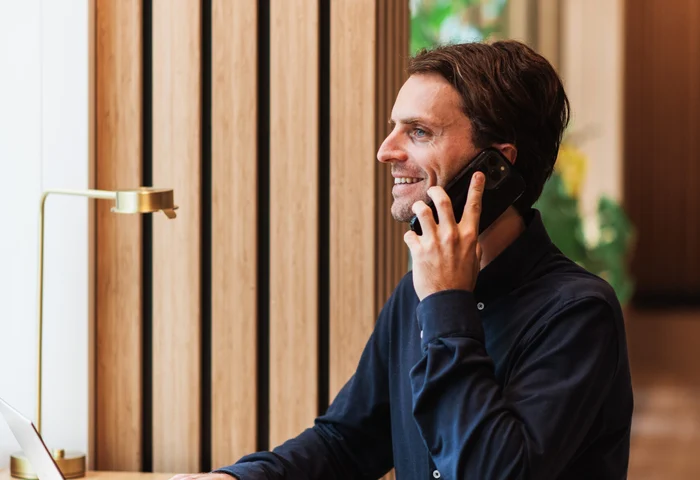 Man i kontorsmiljö som pratar i telefon framför sin dator