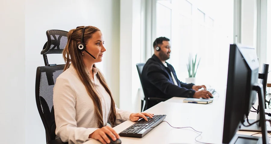 Man and woman conducting background checks at separate computers in an office environment
