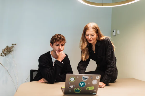 A female employee shows a colleague how employee credit checks work on her work laptop
