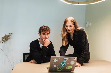 Twee collega's kijken naar een laptop en hebben een gesprek