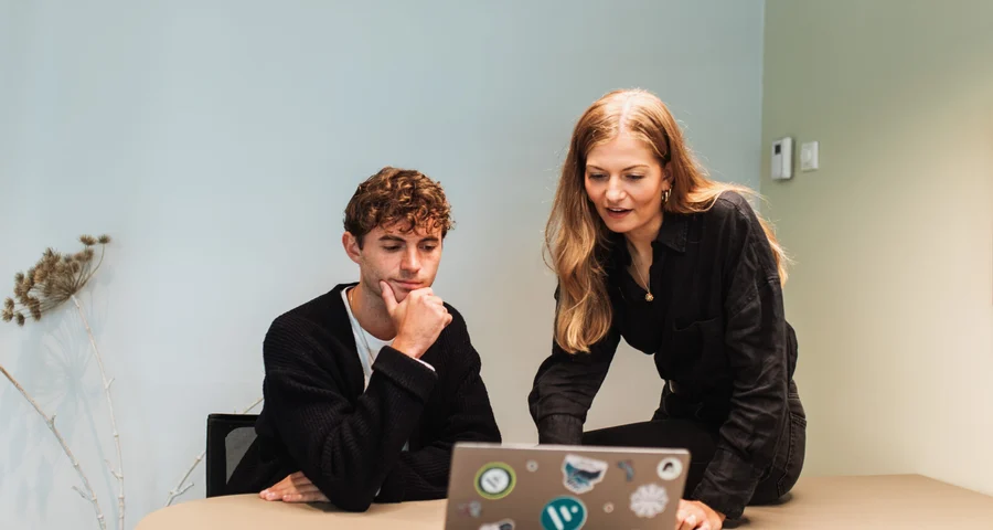 Twee collega's die op kantoor aan een laptop werken