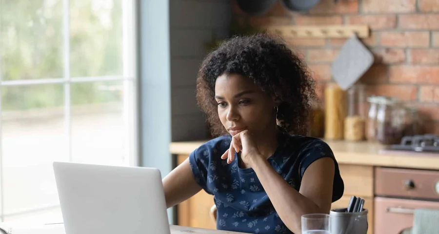 A woman sits at the computer looking for information on background checks for a job application