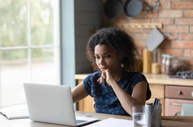 A woman sits at the computer looking for information on background checks for a job application