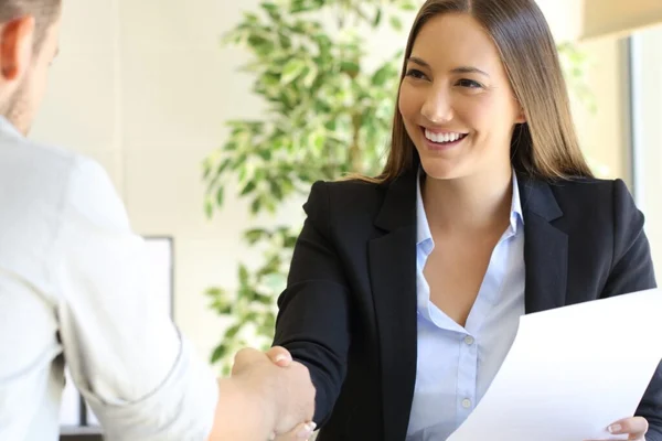 A woman shakes hands with a man while holding a printed inspection report