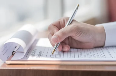 Hand holding a pen filling out an application for employment