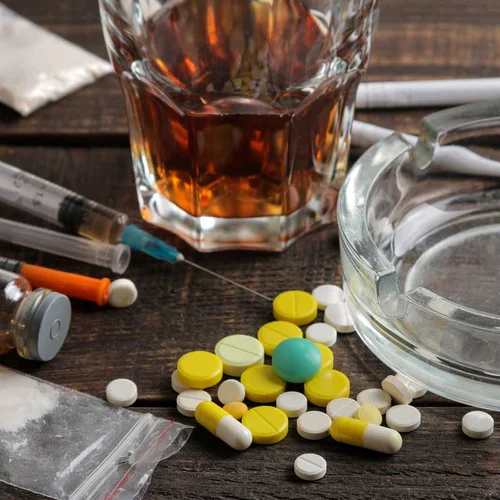 Various addictive drugs including alcohol, cigarettes, and drugs on a brown wooden table. Drug test