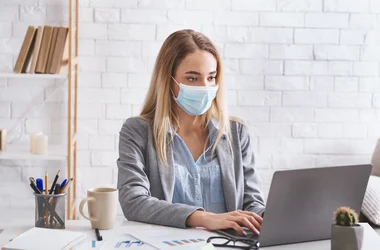 employee working on laptop with covid mask