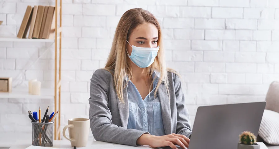 employee working on laptop with covid mask