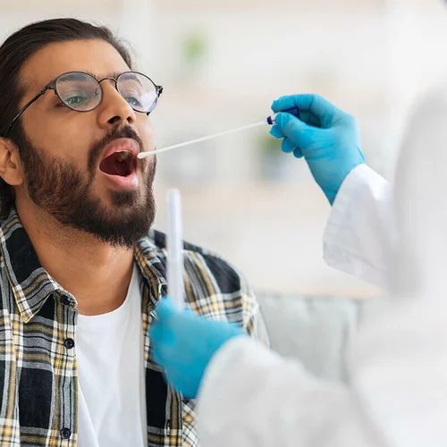 lab technician using a swab to collect oral fluid for testing
