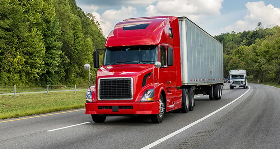 Bright red 18-wheeler truck driving on the road