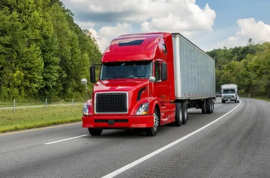 Bright red 18-wheeler truck driving on the road