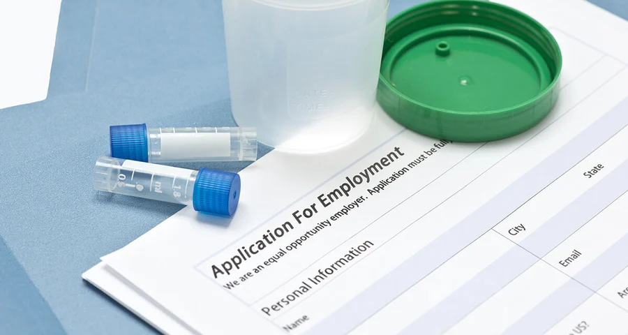 Drug test specimen collection containers sitting on an employment application