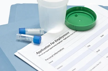 Drug test specimen collection containers sitting on an employment application