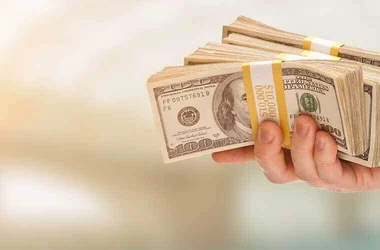 person holding a large sum of money / stacks of $100 bills