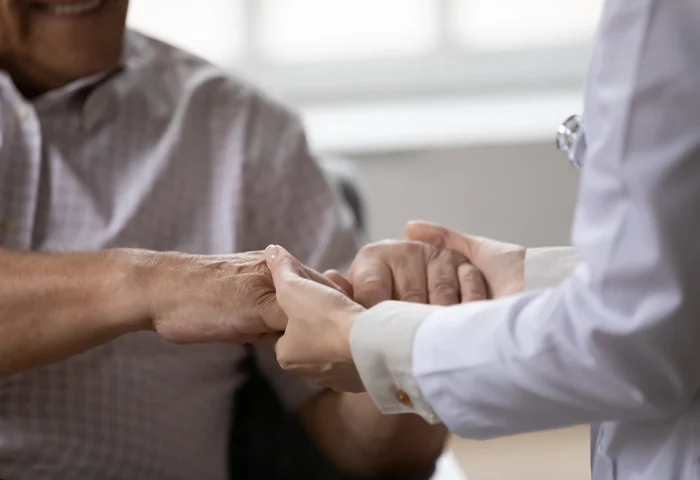 patient and doctor holding hands