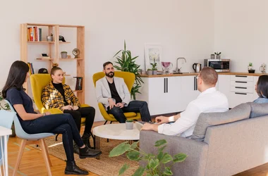 Grupp med människor sitter i en soffgrupp i en skandinavisk kontorsmiljö.