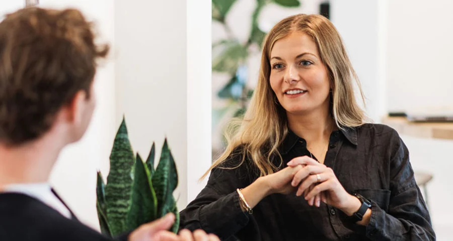 En leende kvinna intervjuas på ett kontor av en man.