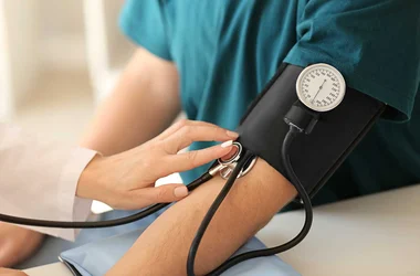 Female healthcare worker measuring blood pressure of male patient for physical exam